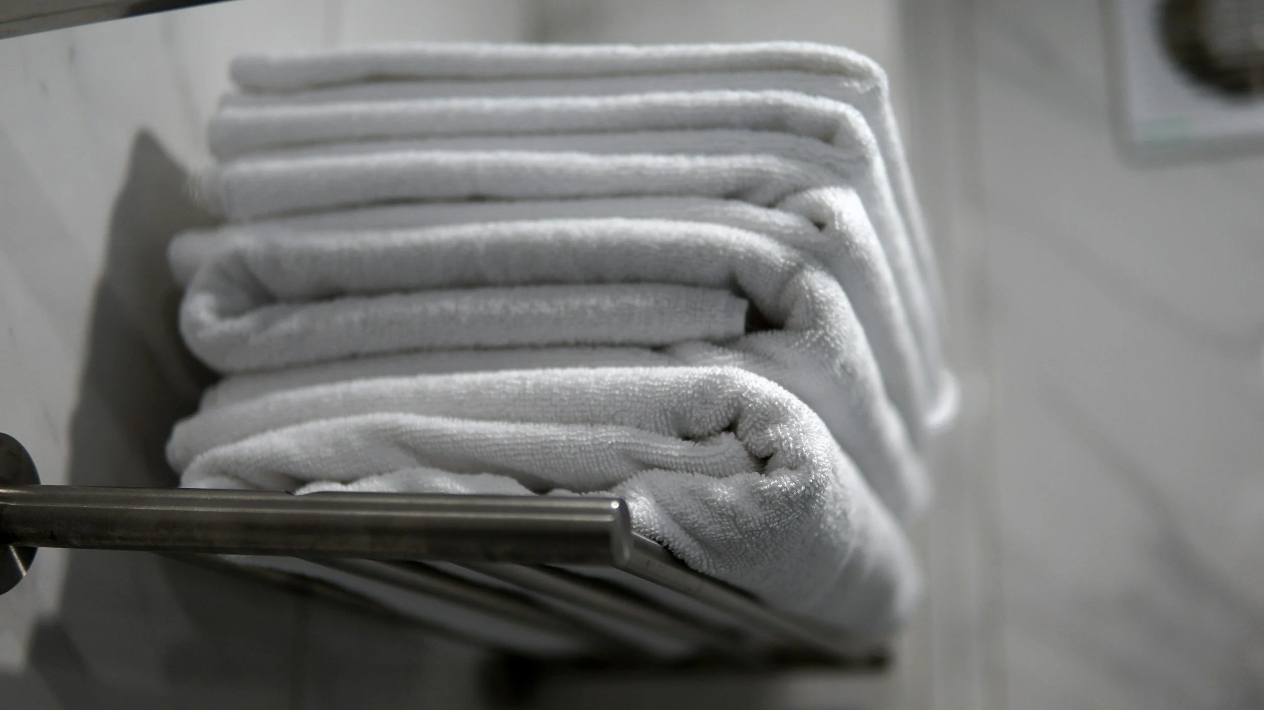 White towels stacked on a metal rack in a laundry or storage area.