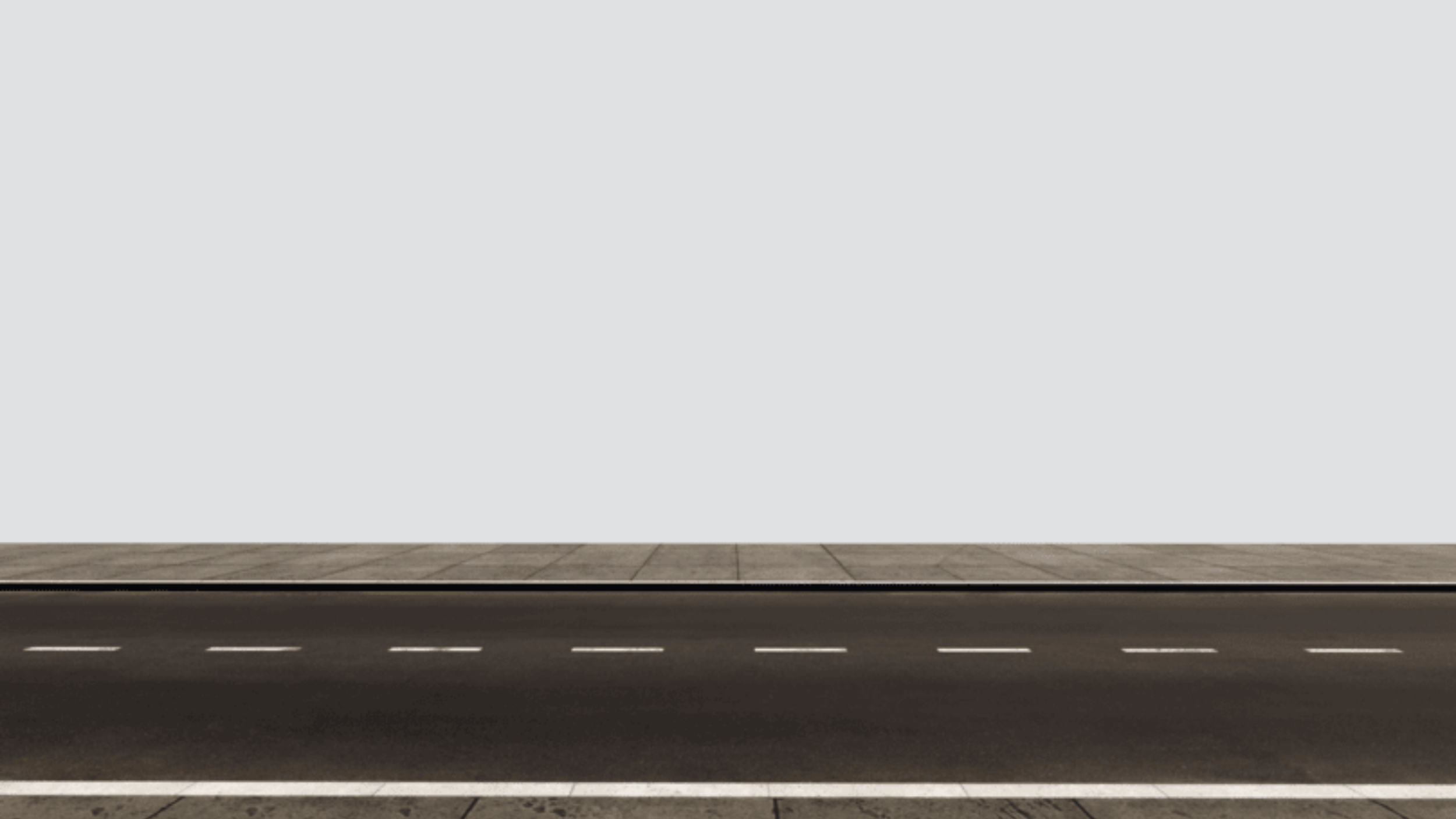 Empty street with asphalt road and sidewalk against blank gray wall.