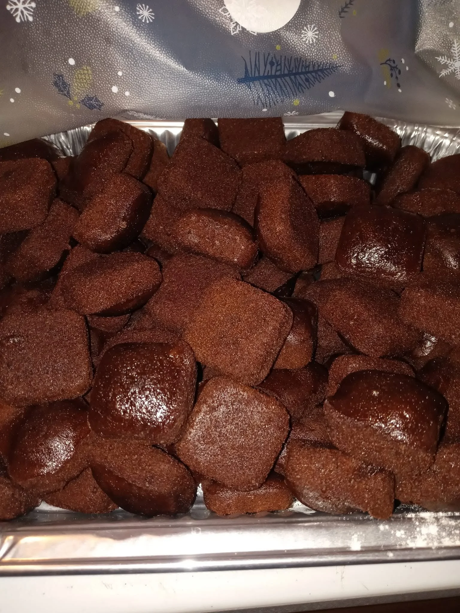 Close-up view of a tray filled with browned, cooked sausage links, with a decorative festive foil underneath.