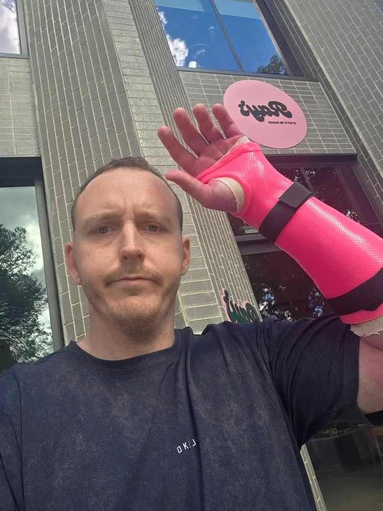 Dr Joshua Saxton wearing a bright pink cast following wrist surgery.
