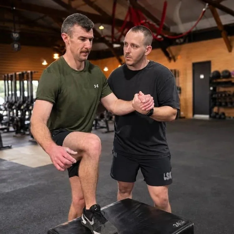 Dr Josh Saxton supporting a patient through a step-up exercise to rebuild movement confidence during rehabilitation.