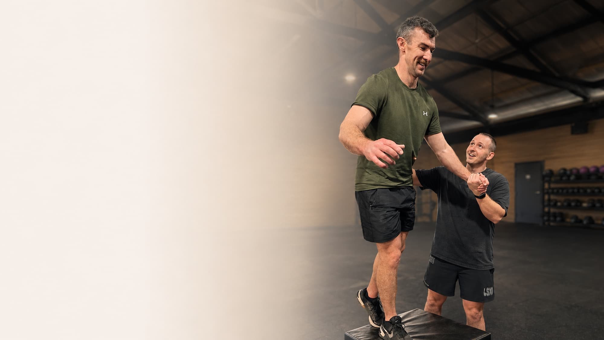 Dr Josh Saxton guiding a patient through a step-down rehabilitation exercise in an Adelaide gym.