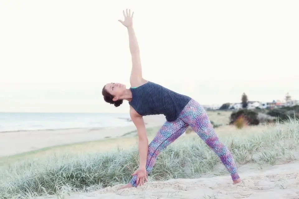 Dr Rosalind Hill practicing yoga on a beach.