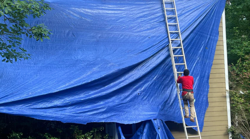 Protective tarp covering siding and landscaping before roof tear-off in Garner, NC 