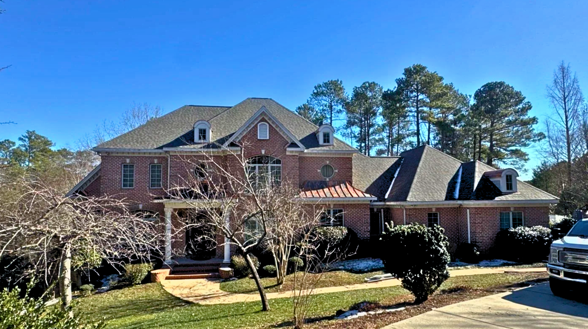 Two story brick home with new roof, Certainteed asphalt shingles in Weathered Wood color, new custom hooded gutter guards, and copper accents