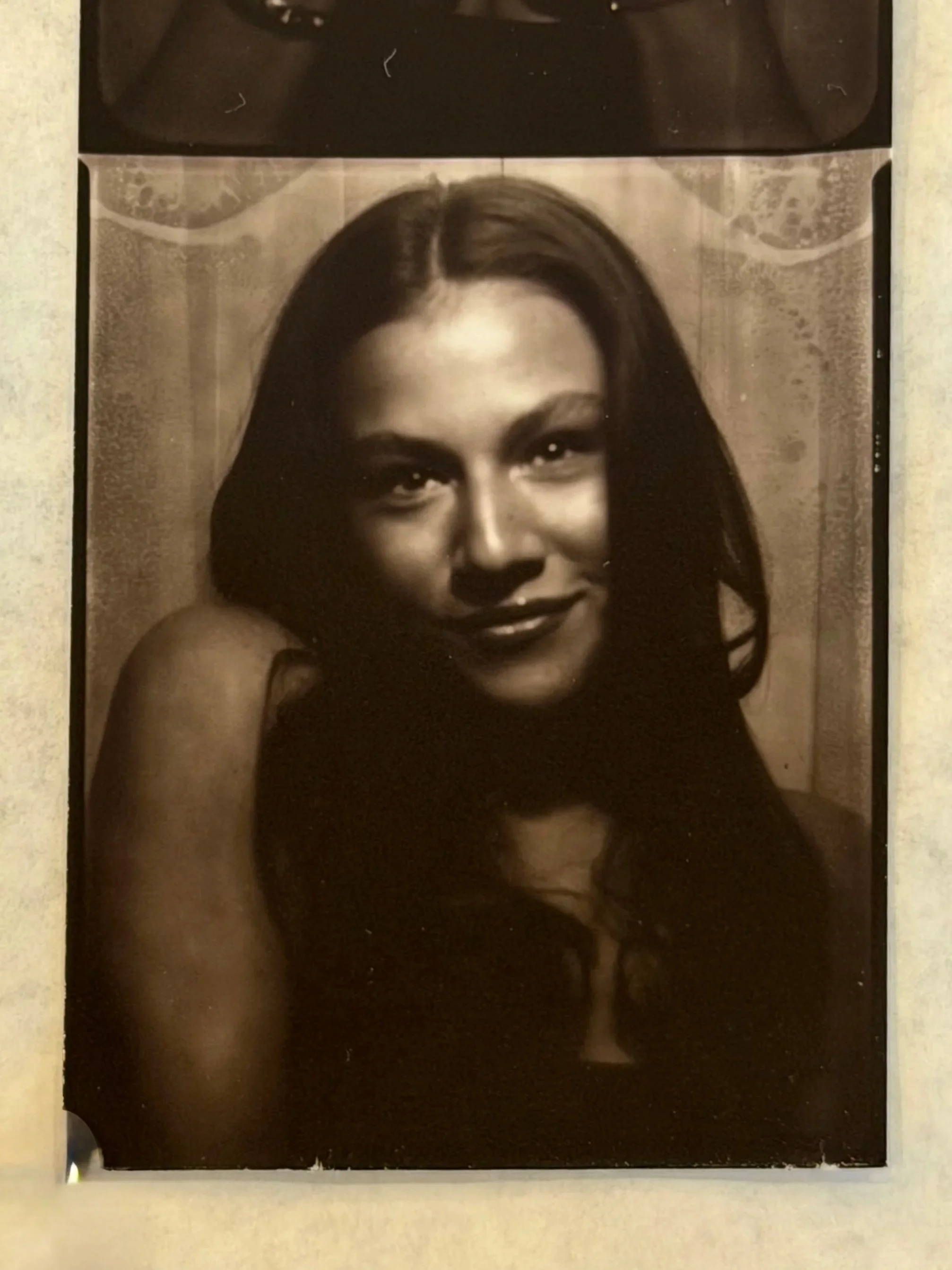 Black and white photograph of a woman with long hair, looking at the camera, with a slight smile.