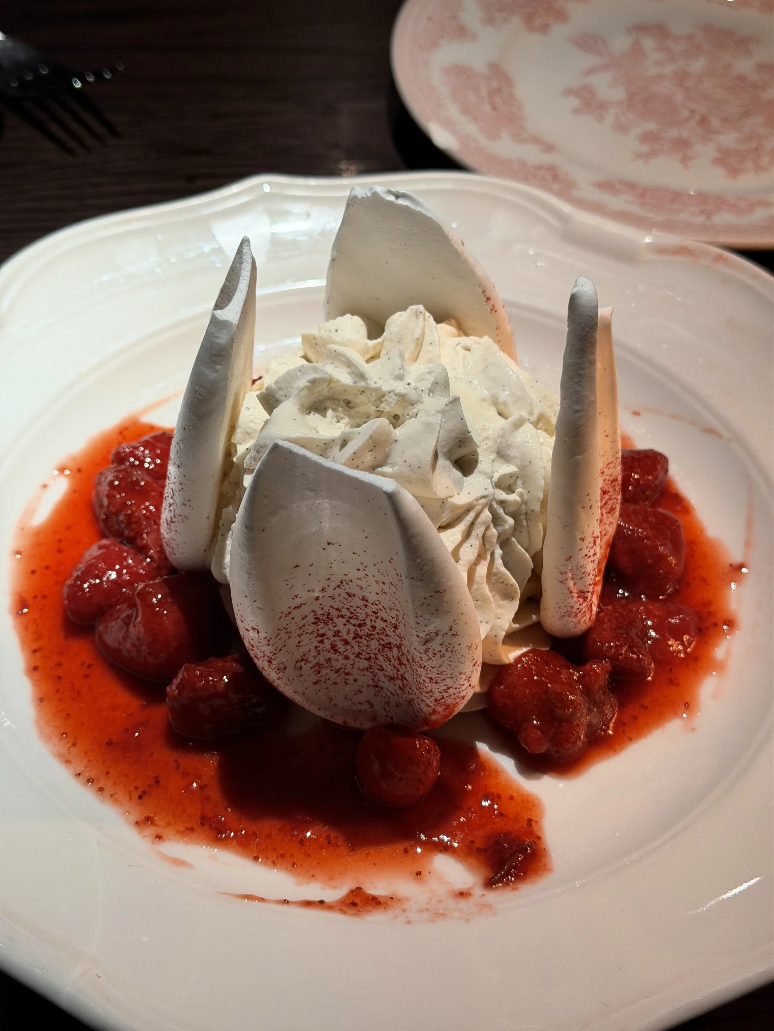 Strawberries with whipped cream and strawberry sauce on a white plate.