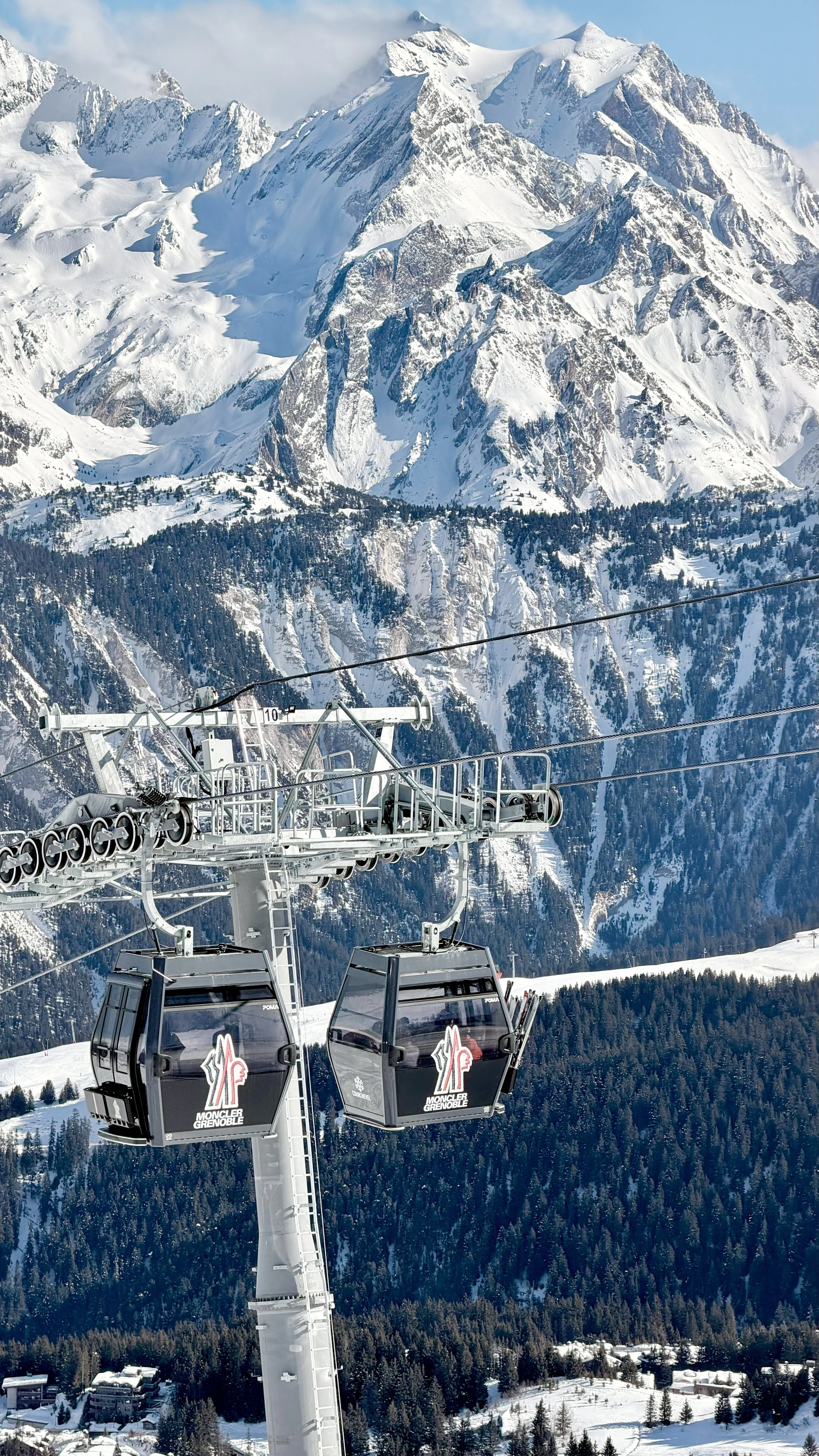 Ski lift in snowy mountains with rugged, snow-covered peaks and forested slopes in the background.