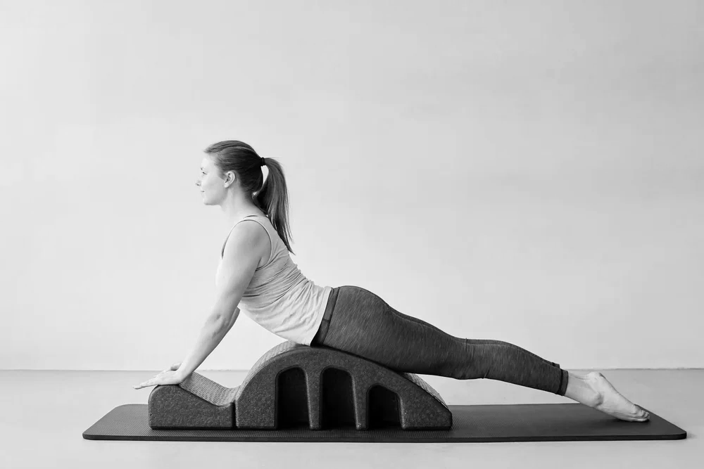 A woman practicing Swan on a Spine corrector.