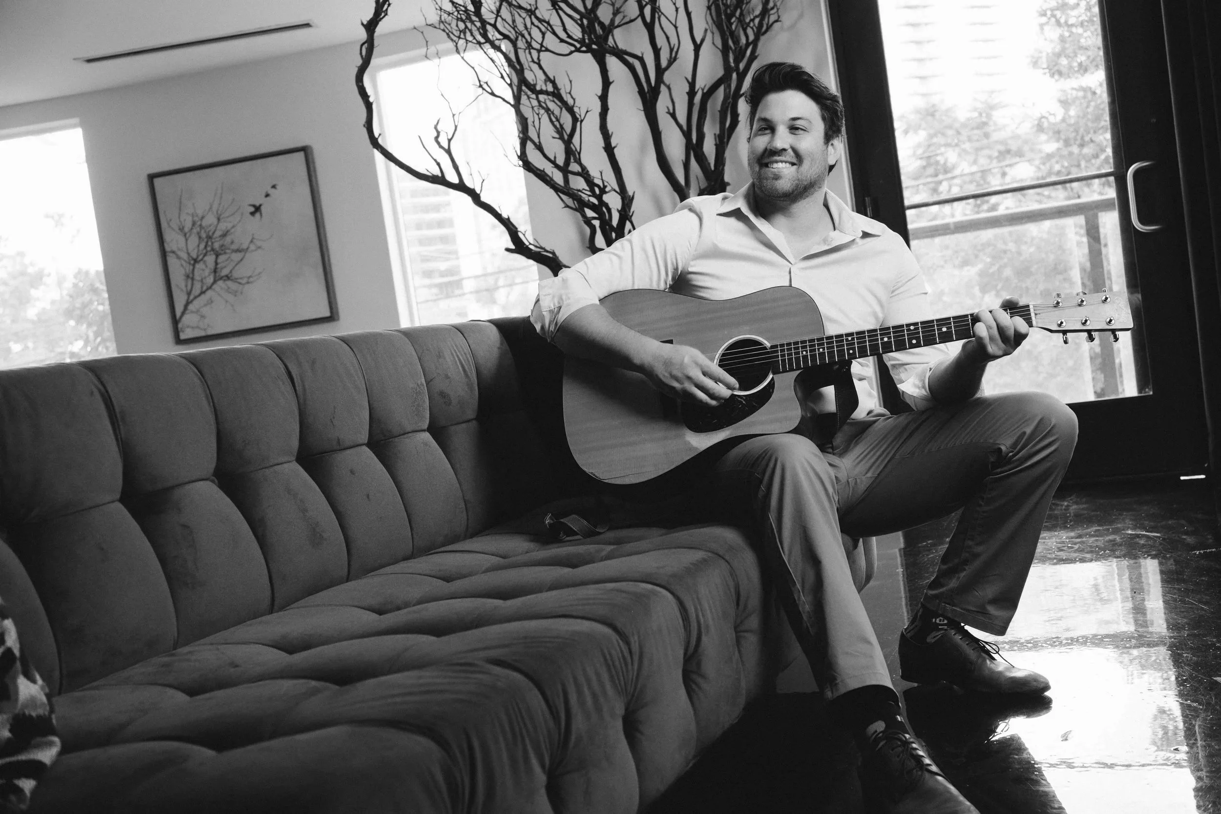 Nashville musician on a sofa playing an acoustic guitar
