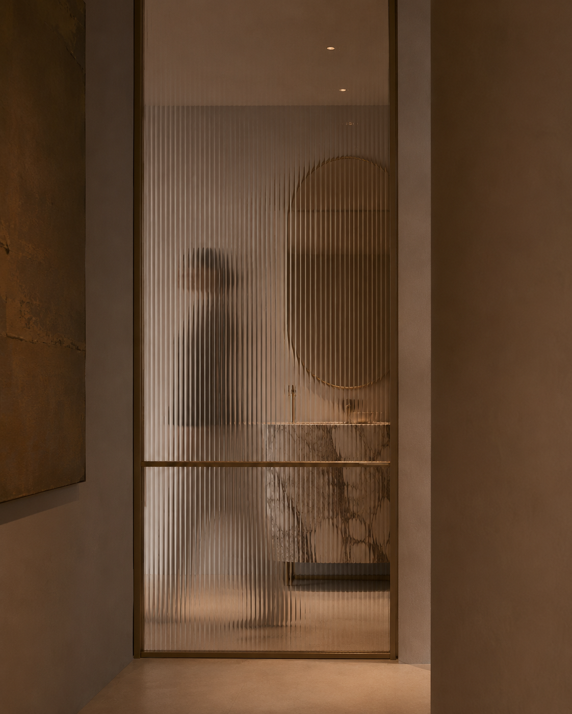 A person reflected behind a ribbed glass door in a modern, dimly lit interior.