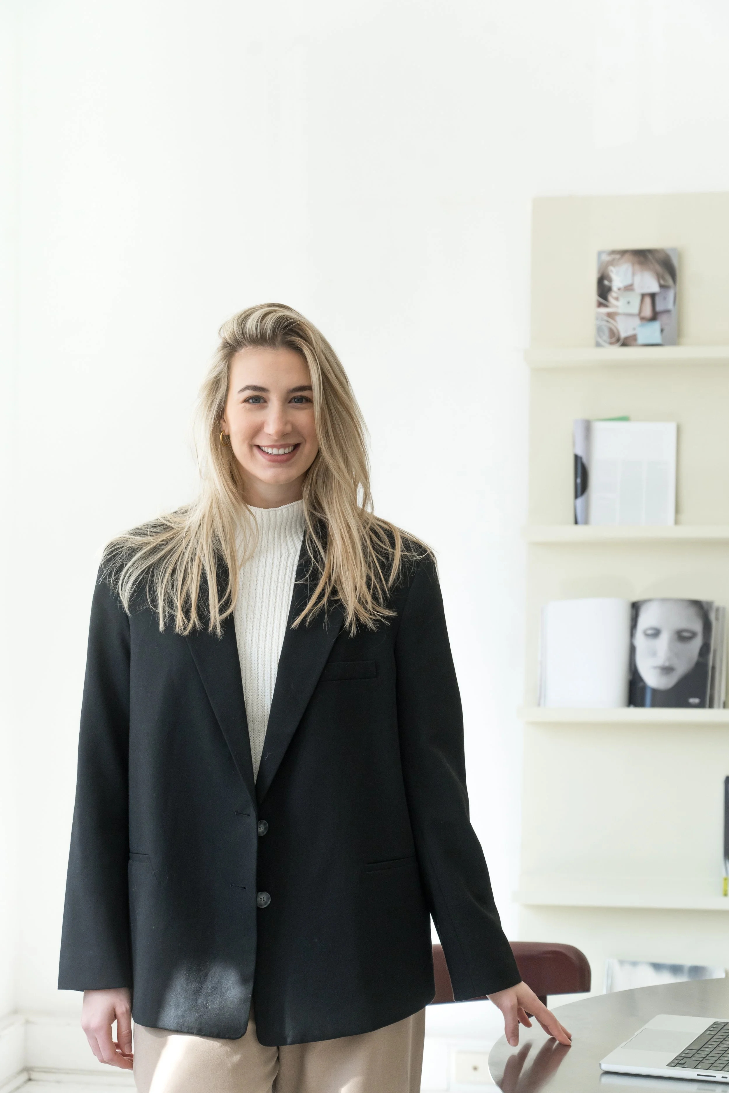 Lauren Poulos, psychologist, standing in a bright office in a black blazer