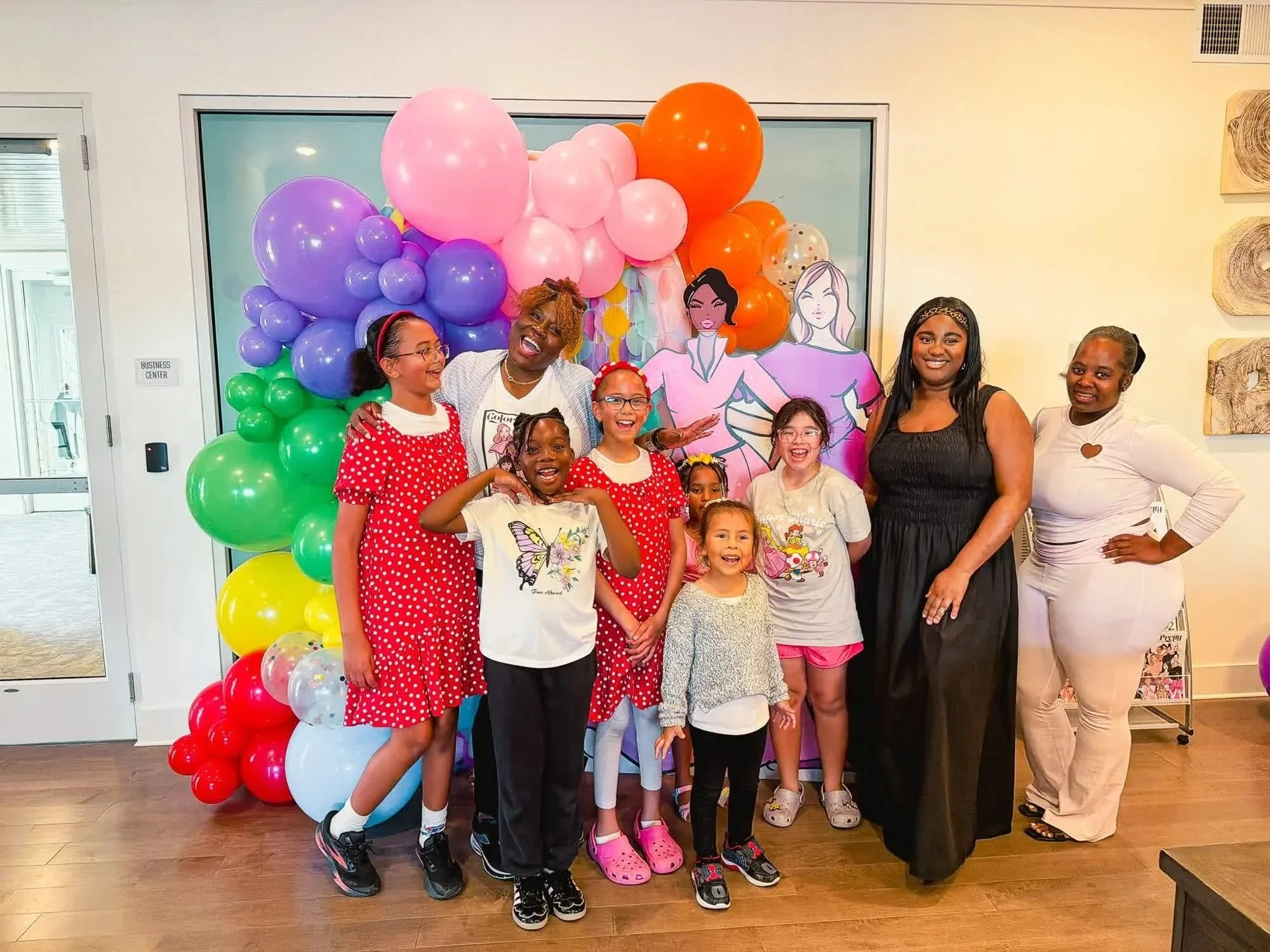 Group of attendees posing in front of a colorful balloon arch at a Color In Pretty community event