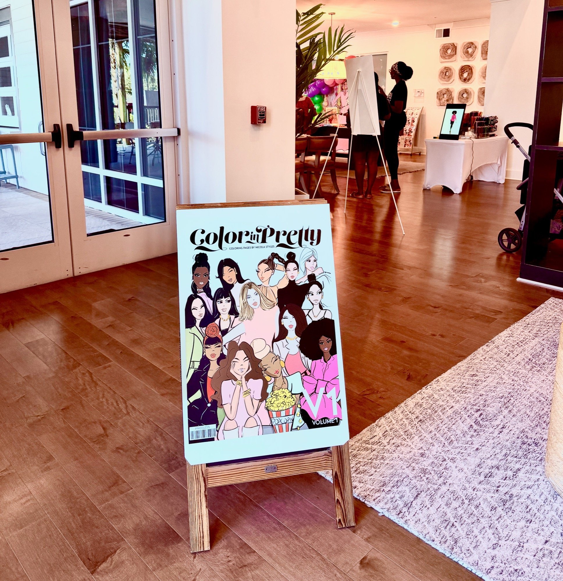 A colorful illustrated poster featuring diverse women with various hairstyles, posing confidently, with a popcorn bucket and volume number at the bottom, advertising a coloring project called 'Color in Pretty'.