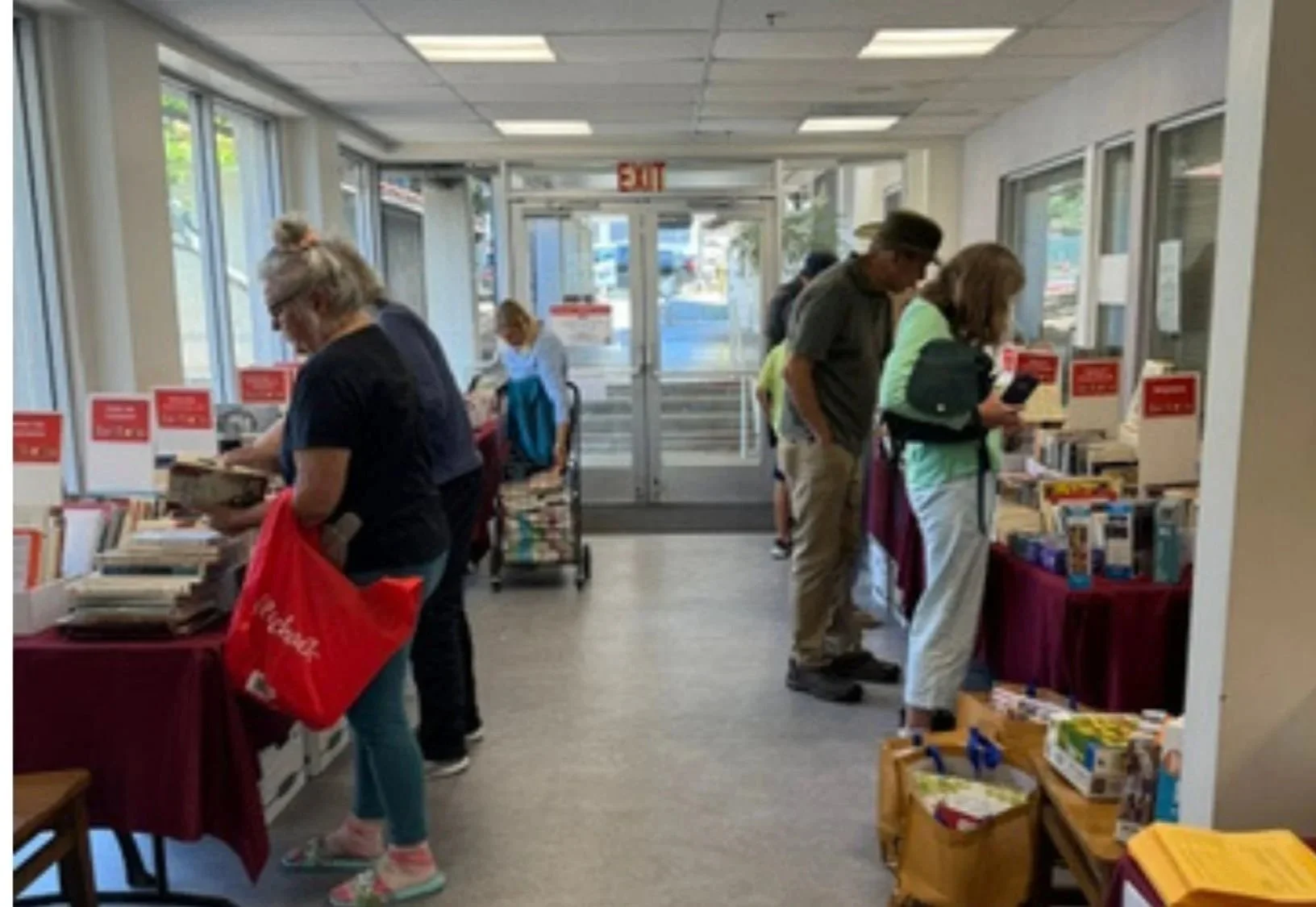 People shopping at a bookstore with books on tables and shelves near the entrance.