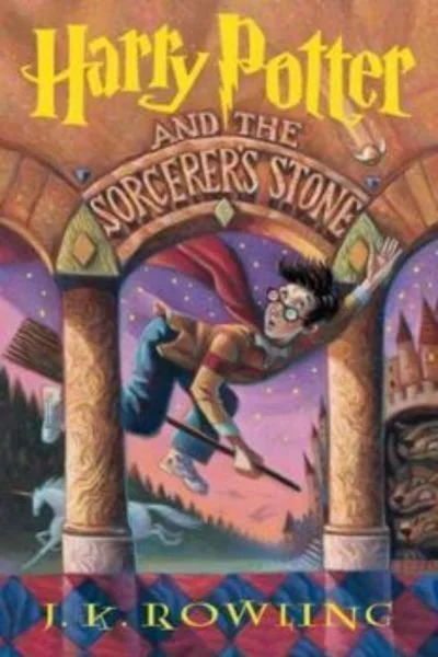 Book cover of Harry Potter and the Sorcerer's Stone by J.K. Rowling, depicting a young wizard in a cape flying on a broomstick through an archway with a purple sky and castle in the background.