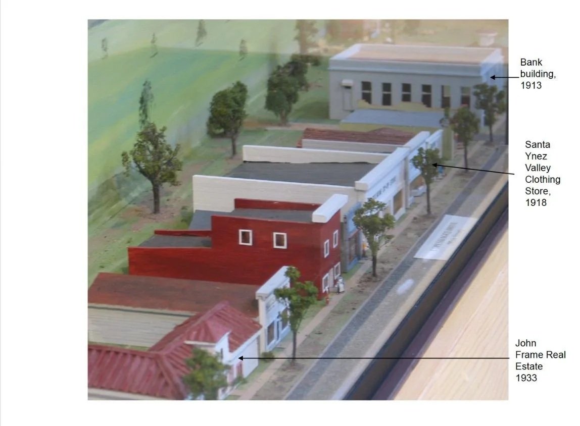 A scale model of buildings and trees representing historic structures, including a bank building from 1913, a Santa Ynez Valley clothing store from 1918, and a John Frame real estate building from 1933.
