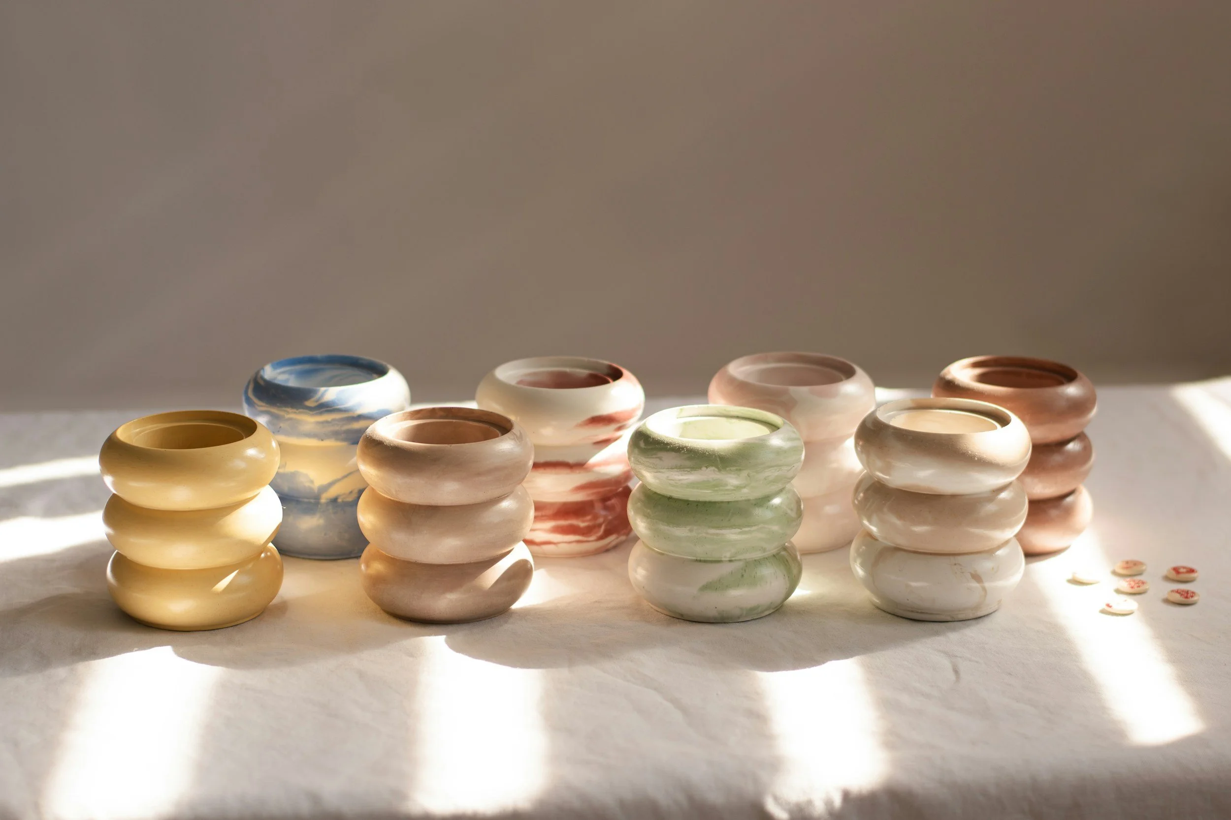 Multiple marbled ceramic pottery pieces arranged on a surface with shadows cast by natural light.