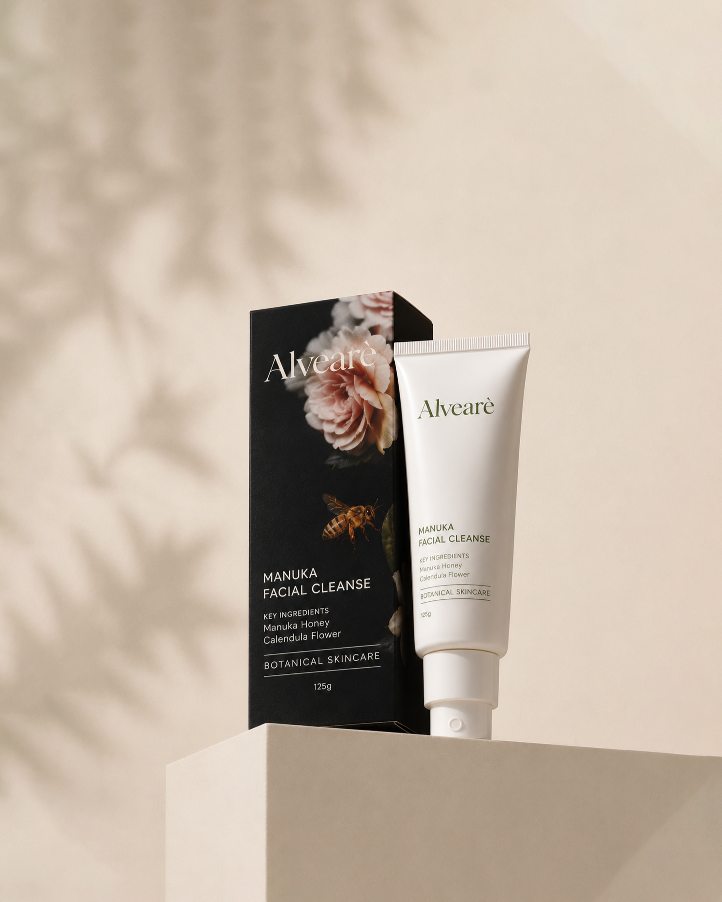 A tube of Alvear Manuka Facial Cleanse standing upright next to its black packaging box with floral and bee graphics, against a minimalist background.