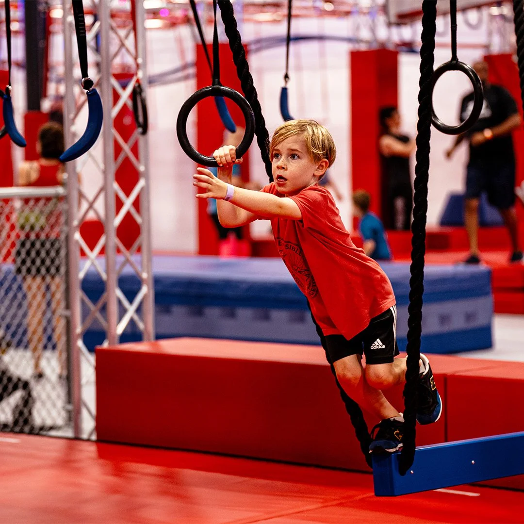 Child swinging between obstacles at Octo Ninja indoor obstacle gym in Austin