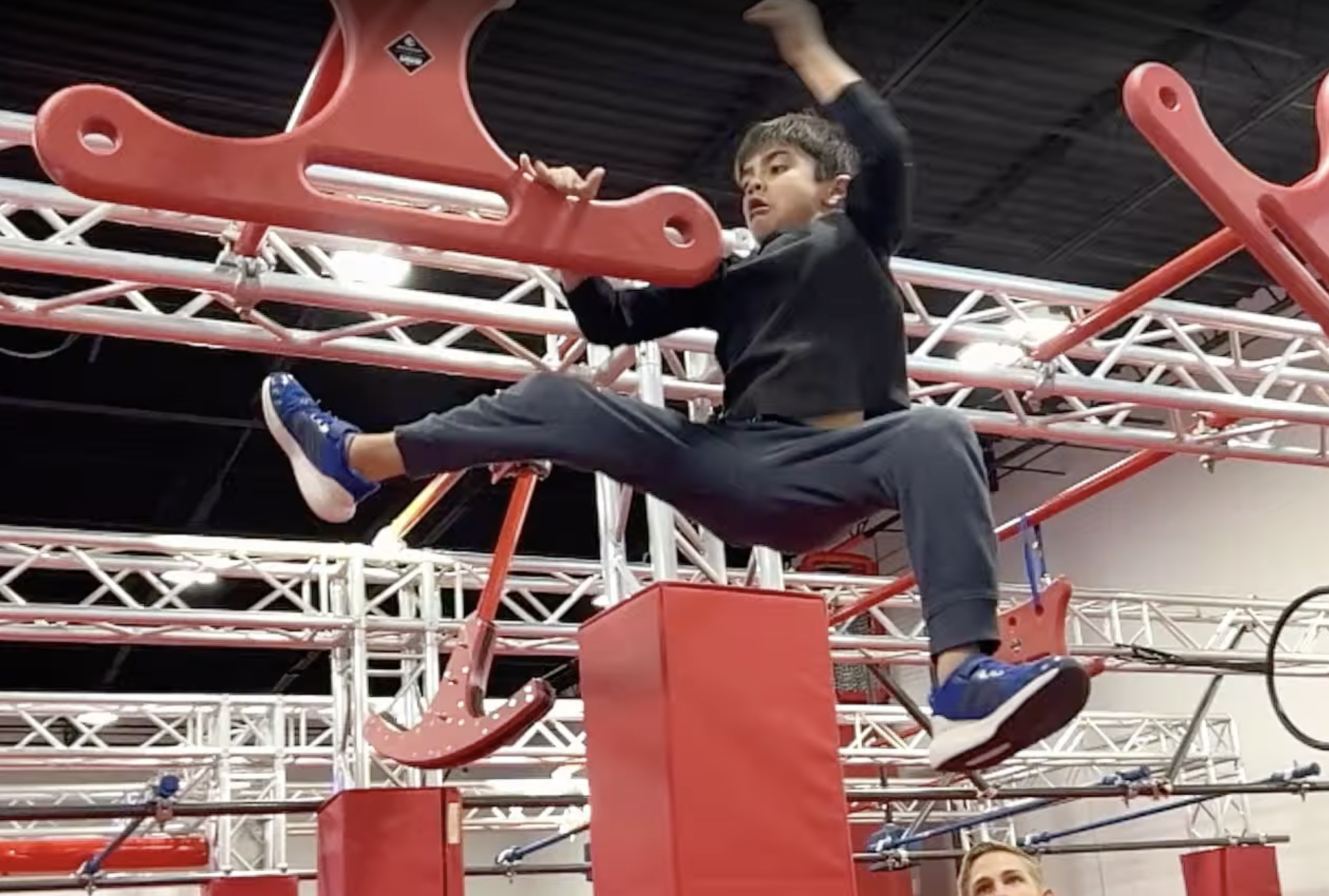 Child climbing an overhead ninja obstacle at Octo Ninja Summer Camp in Austin Texas