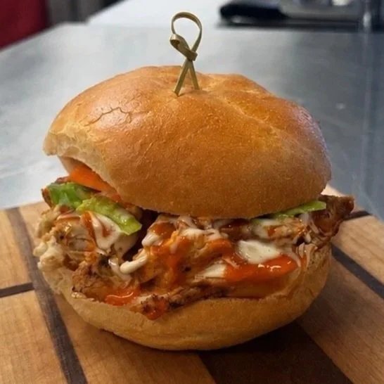 BBQ pulled pork sandwich with lettuce and sauce on a bun, held together with a toothpick.
