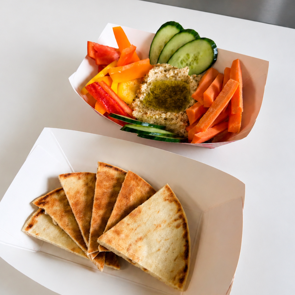 Colorful vegetable platter with cucumber slices, bell peppers, tomato, carrots, and hummus with olive oil, alongside slices of quesadilla.
