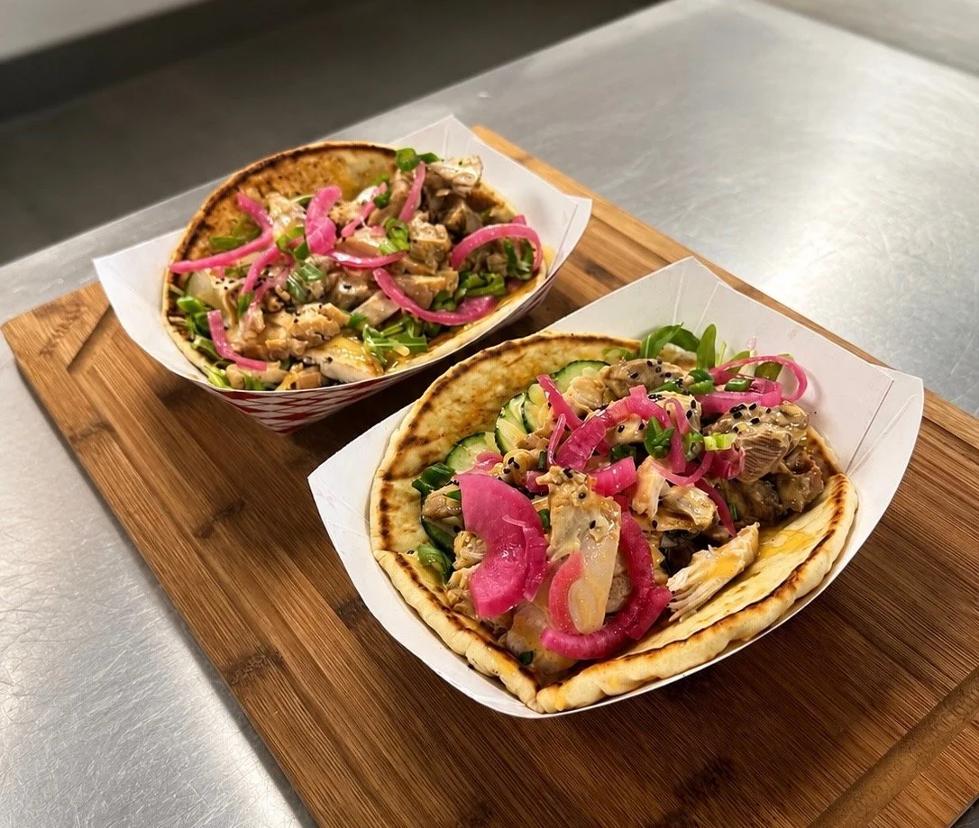 Two Japanese tacos with fresh vegetables and pickled onions placed on a wooden tray.