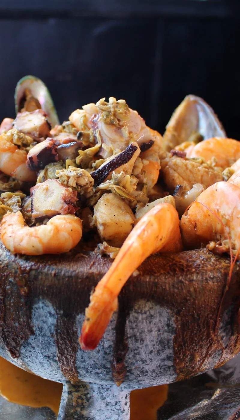 Seafood boil with shrimp, crab, and mussels served inside a hollowed-out grilled corn husk.