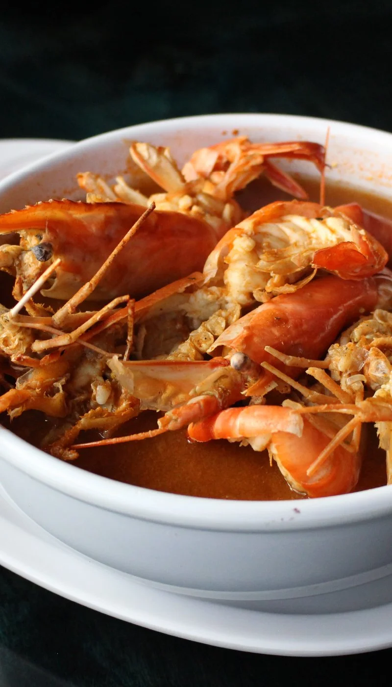Close-up of a bowl of cooked shrimp in a reddish broth