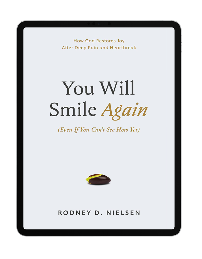 The eBook book cover: 'You Will Smile Again (Even If You Can't See How Yet)' by author and pastor Rodney D. Nielsen. Subtitle: How God Restores Joy After Deep Pain and Heartbreak. The cover is white except for a small seed beginning to grow.