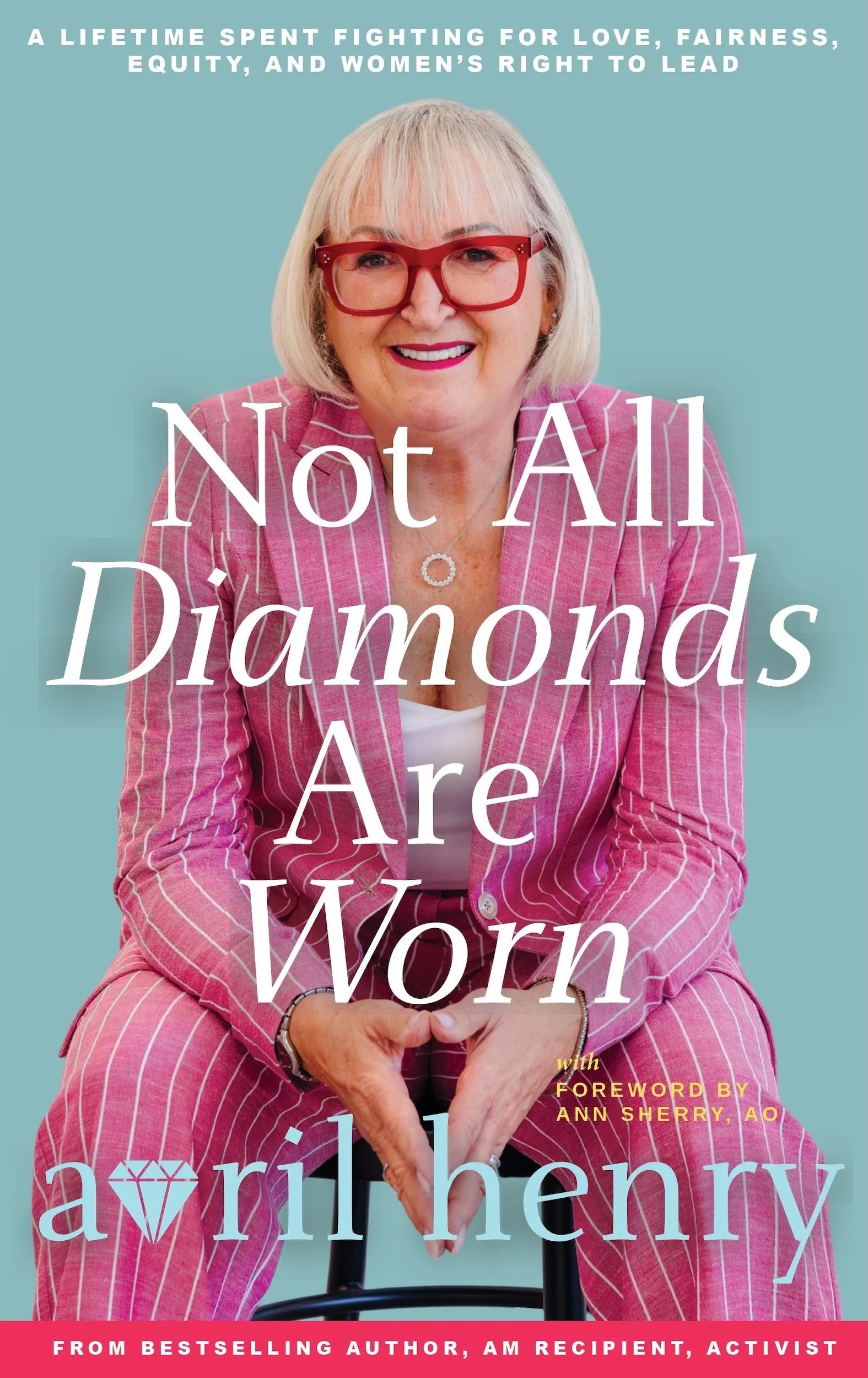 Book cover featuring a smiling woman with blonde hair, red glasses, and a pink striped suit, sitting against a light blue background. The title reads 'Not All Diamonds Are Worn' by Avril Henry, with a foreword by Ann Sherry, AO. The top text states 'A lifetime spent fighting for love, fairness, equity, and women's right to lead.' A callout at the bottom mentions she is an bestselling author, AM recipient, and activist.