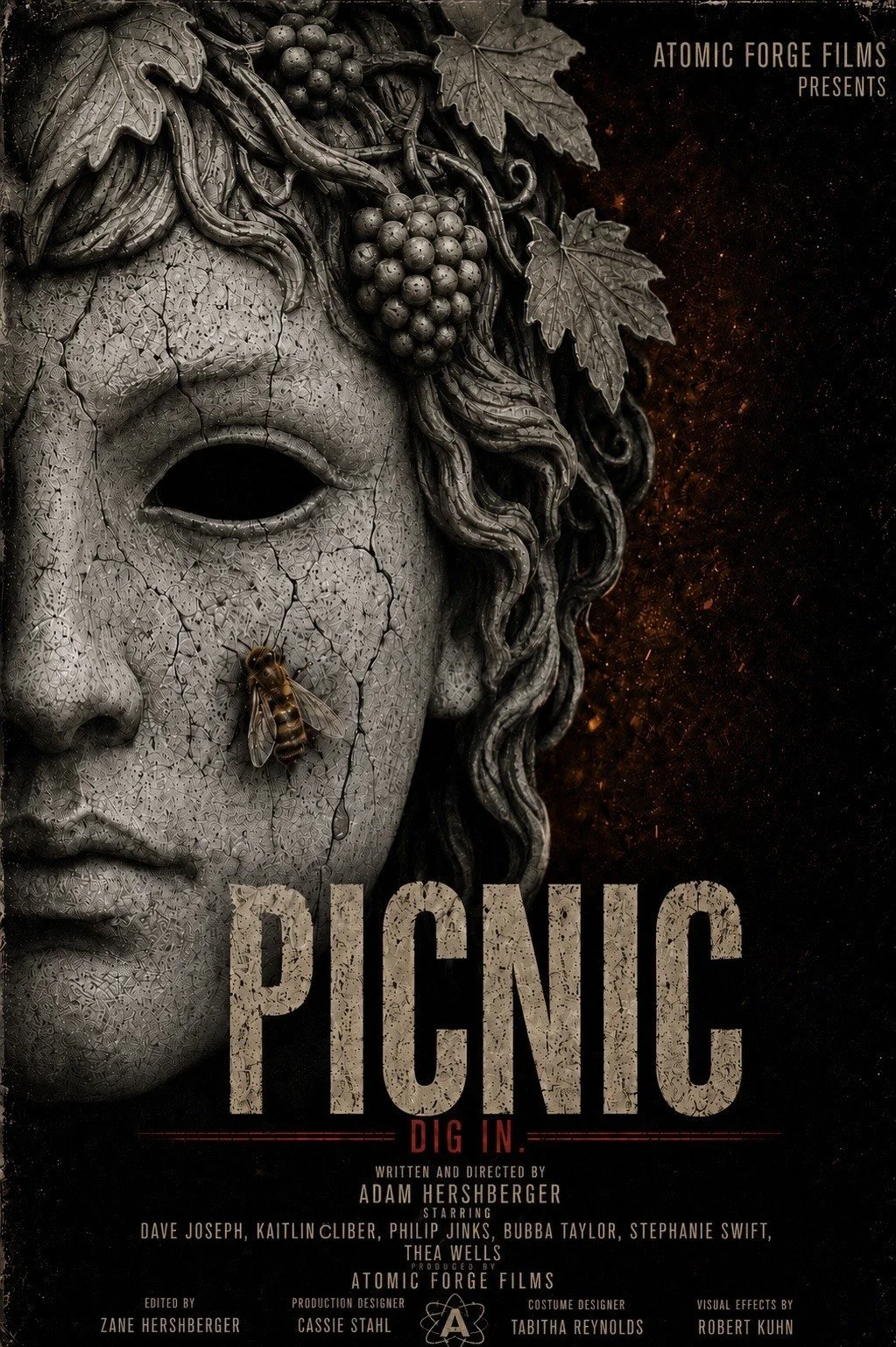 A promotional poster features a cracked stone mask resembling a human face with hollow eyes. A bee is perched on the cheek, and grapevines with grapes and leaves are intertwined at the top of the mask. The background is dark with scattered reddish-orange sparks. The poster is for a film titled 'Panic: Dig In,' produced by Atomic Forge Films, with credits for the writer, director, cast, and crew.
