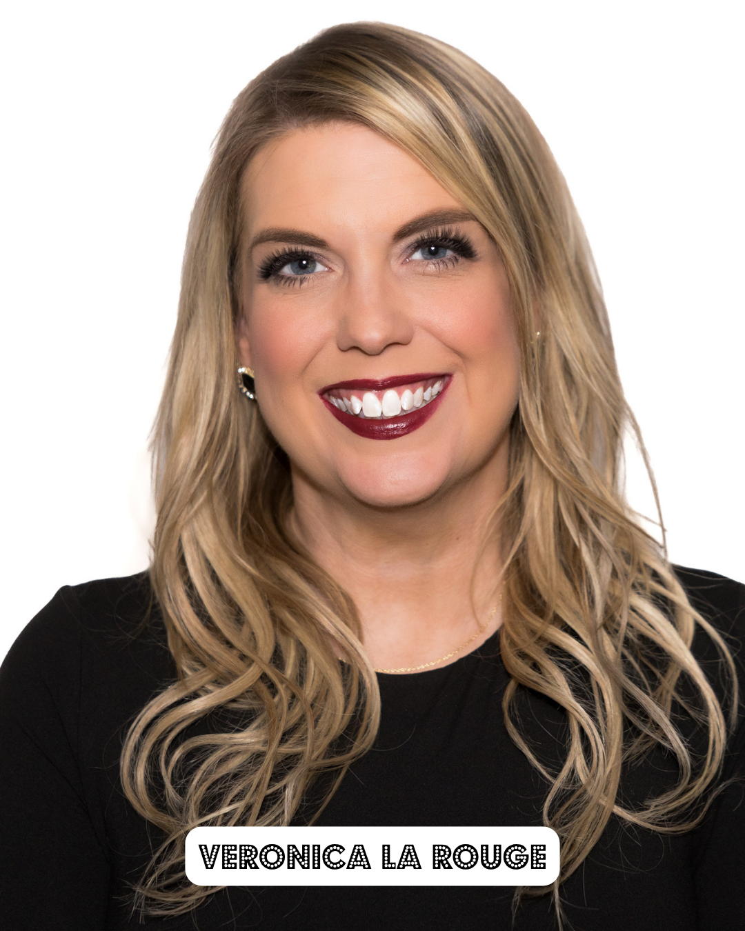 A woman with long blonde hair, wearing makeup including dark lipstick, smiling and wearing a black top, with the text 'Veronica La Rouge' at the bottom.