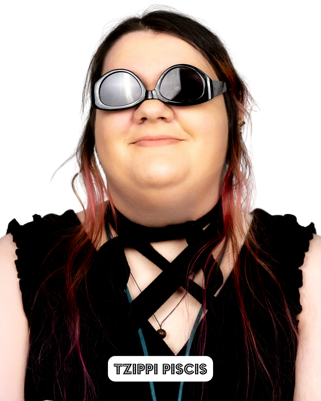 Person wearing swimming goggles and a black top with crossed straps, smiling lightly against a white background.