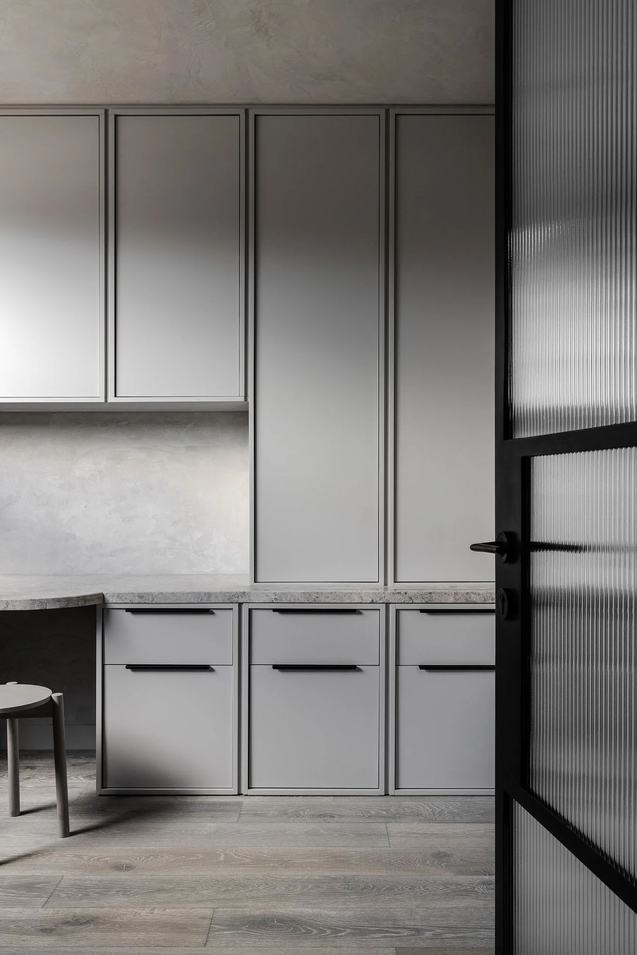 Modern office with gray cabinets, countertop, and wood flooring.