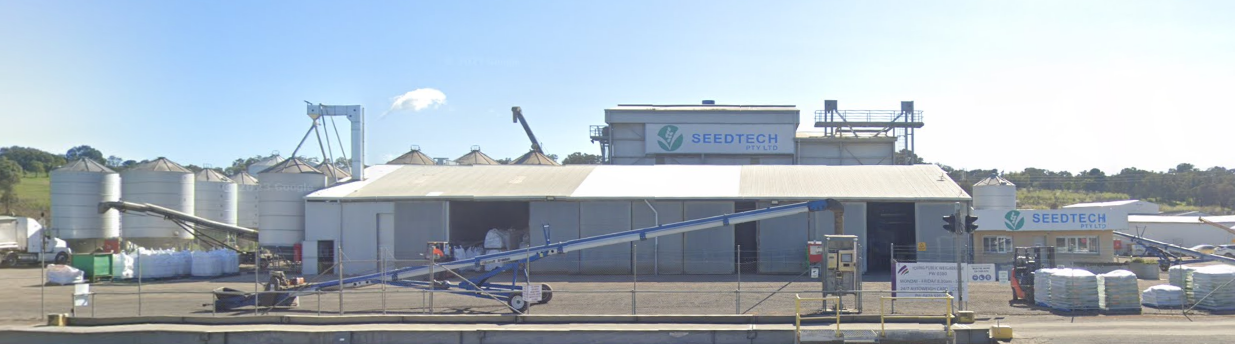 Agricultural seed processing facility with silos, conveyors, and storage bags, branded SEEDTECH.
