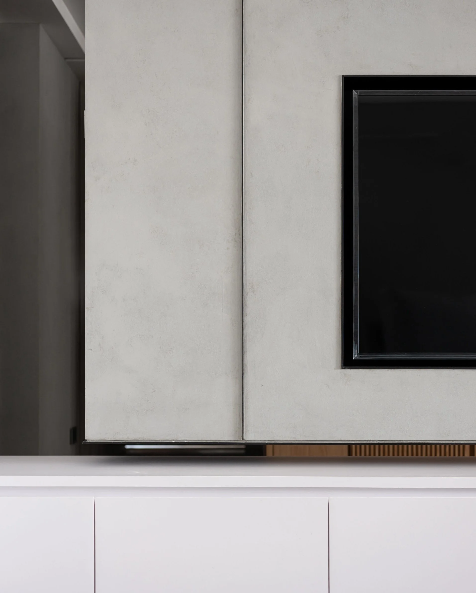 Close-up of a modern kitchen cabinet and television on a white wall