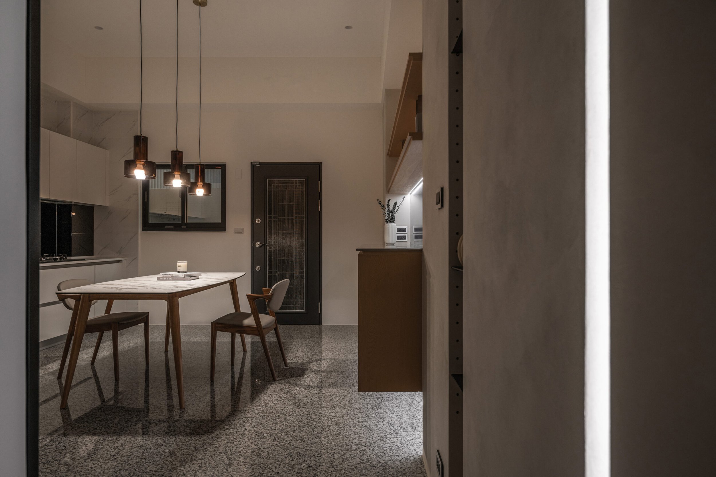 Modern kitchen and dining area with a wooden table, chairs, pendant lights, and decorative items.