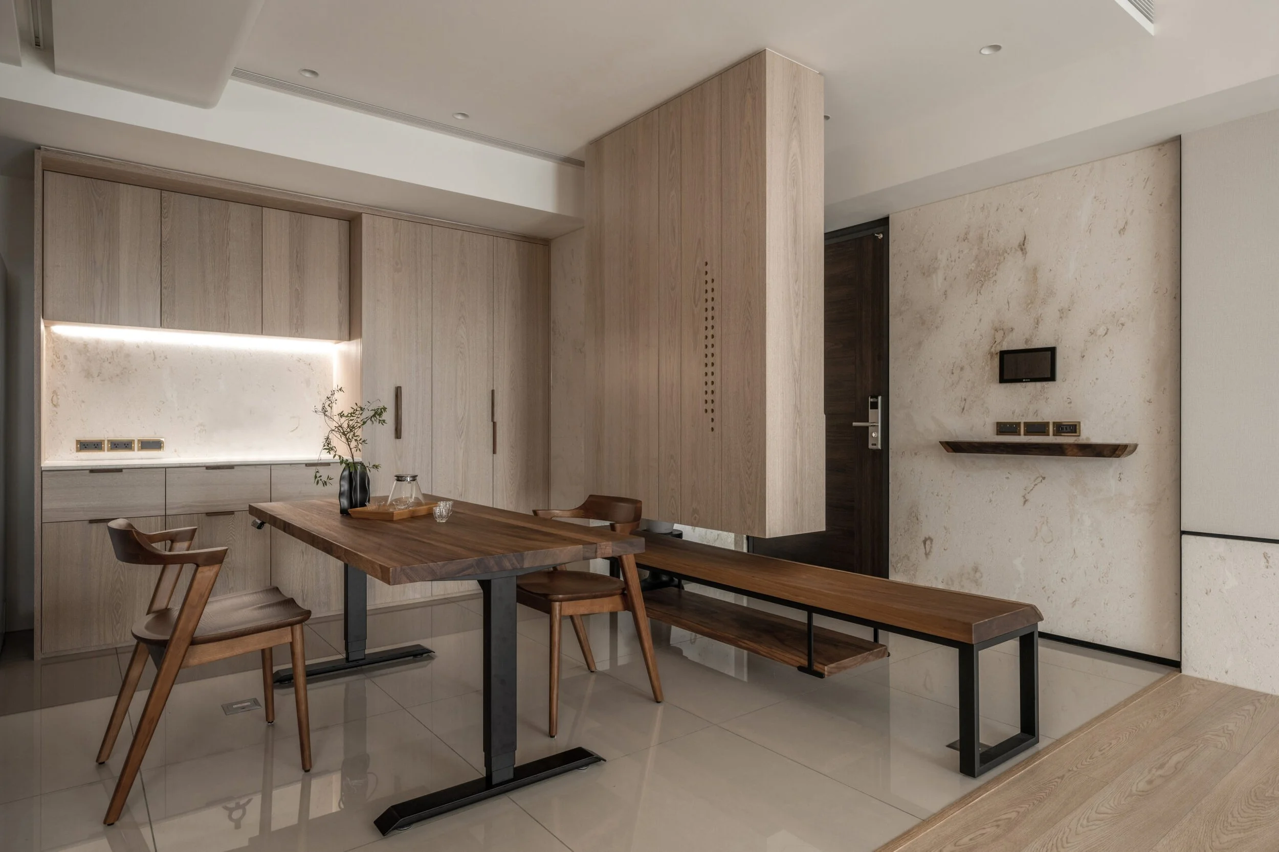 Modern dining area with a wooden table, four chairs, wooden cabinetry, and a TV mounted on a wall with marble accents.