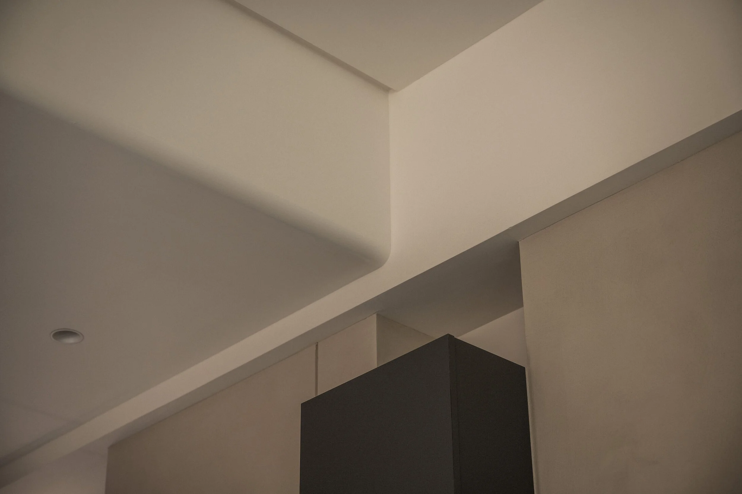 Interior ceiling with white, grey, and black layered architectural panels creating a modern geometric design.