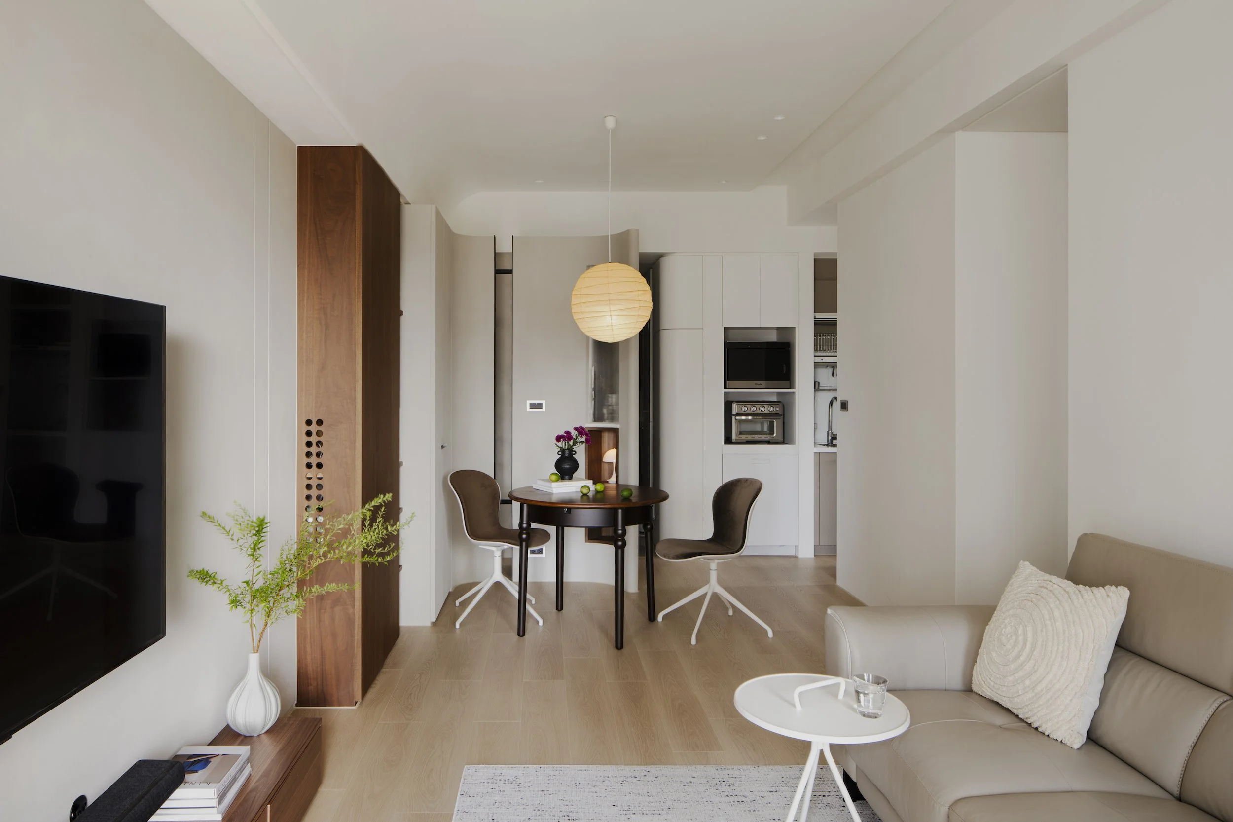 Minimalist living room with a beige couch, white small round side table, and decorative pillows, with a modern design.