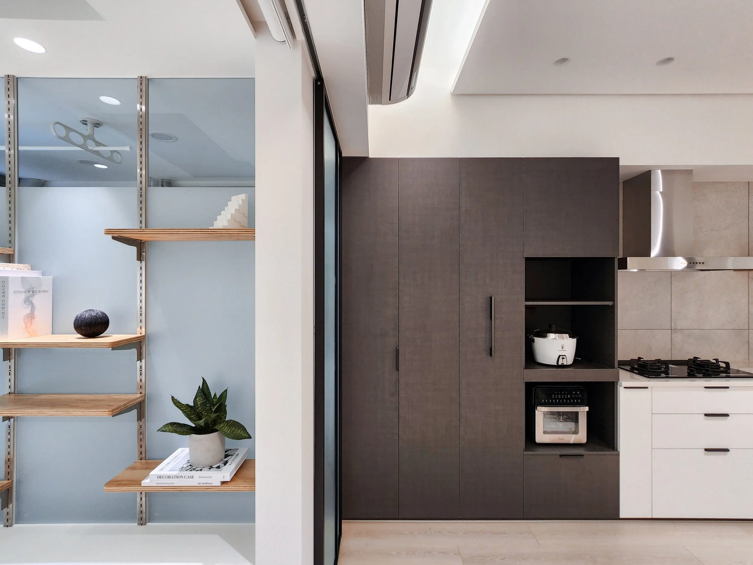 Modern kitchen with built-in oven, dark cabinetry, and open shelves with decorative items.