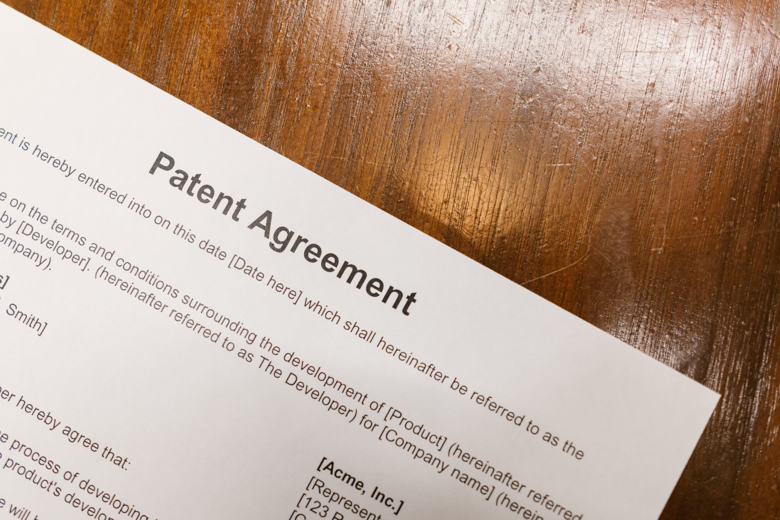 Close-up of a legal document titled 'Patent Agreement' on a wooden desk.