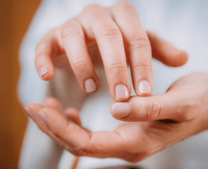 Close-up of a person's hands, with one hand gently touching or holding the other hand.