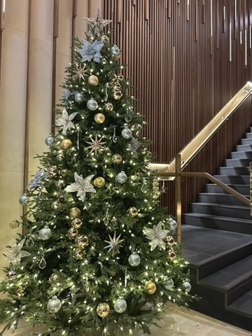 Decorated Christmas tree with gold, silver, and white ornaments and poinsettia flowers in an indoor setting.