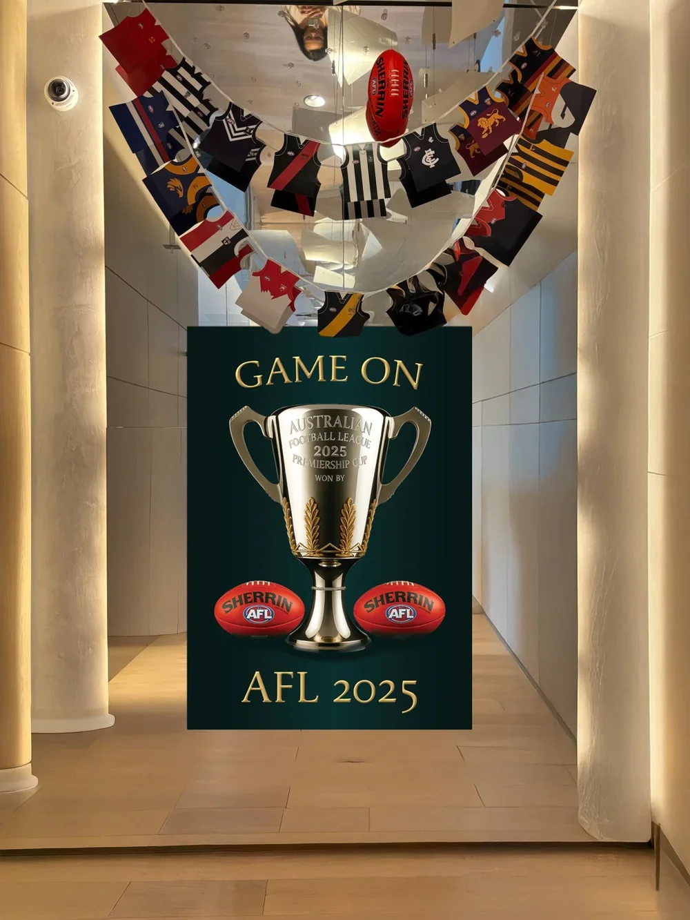 Decorative display celebrating the 2025 Australian Football League premiership with a large poster featuring a trophy and two footballs, and football jerseys hanging above.