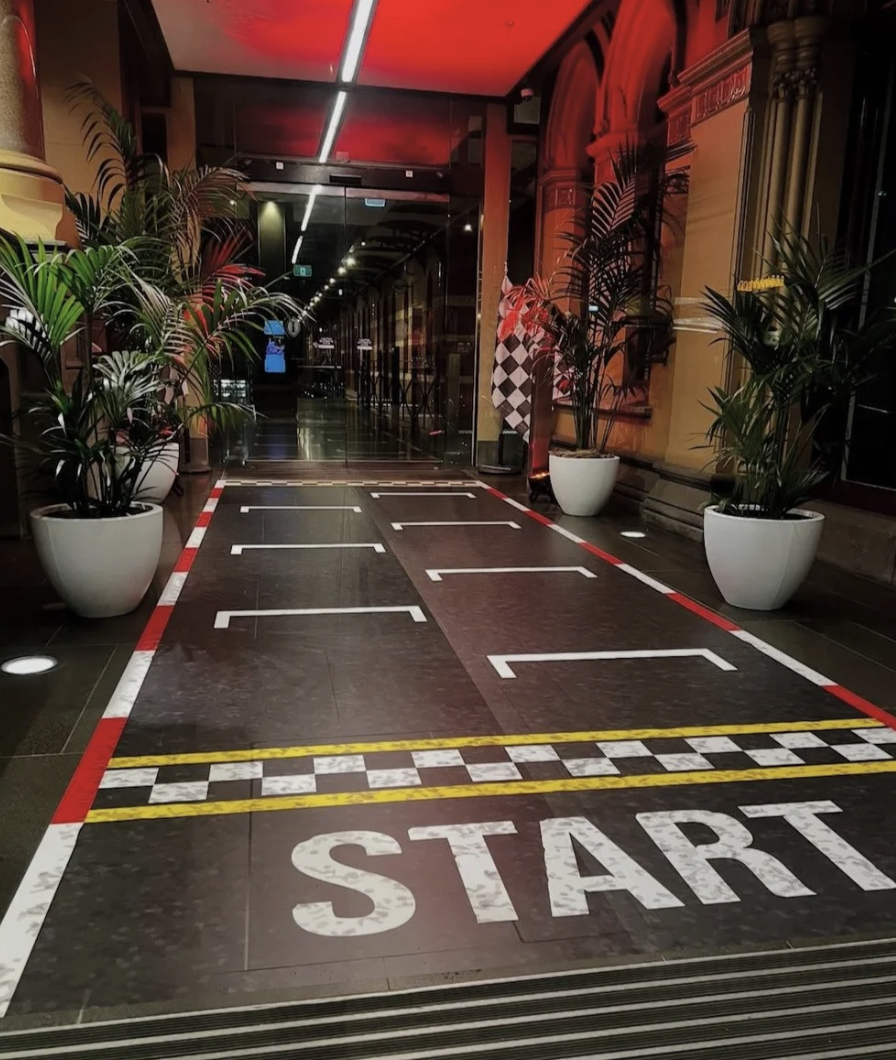 Entrance of the Intercontinental Hotel with a race track layout on the floor, marked with white lines and the word 'START' in large white letters by designers at TELIPOK Cindy Lee and David Swift