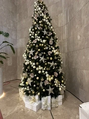 Decorated Christmas tree with silver and gold ornaments, star toppers, and gift boxes underneath.