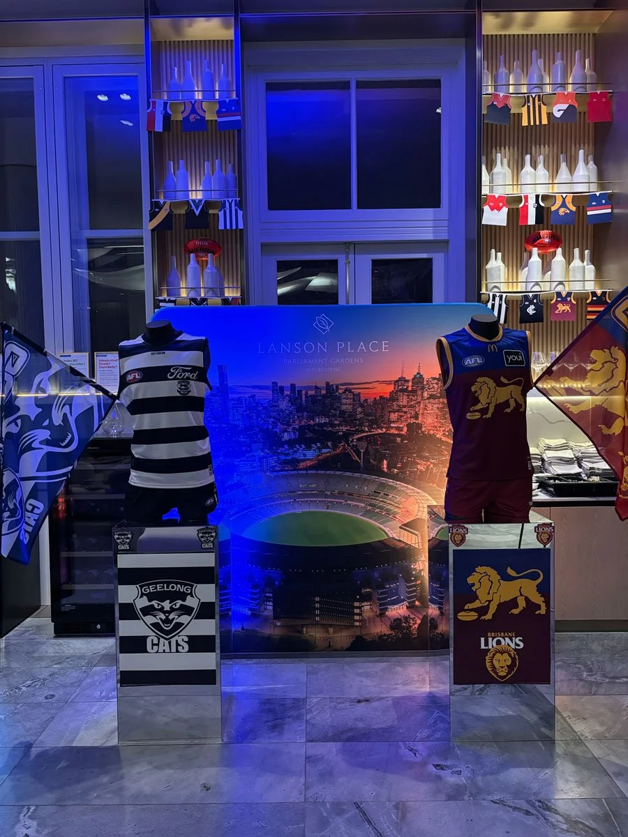 Display of Australian football team jerseys from Geelong Cats and Brisbane Lions at Lanson Place, with decorative bottles and banners in the background.